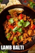 Close up of lamb balti curry in a balti bowl with naan and text overlay.