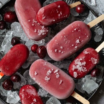 Large and miniature healthy cherry popsicles on a plate of ice.