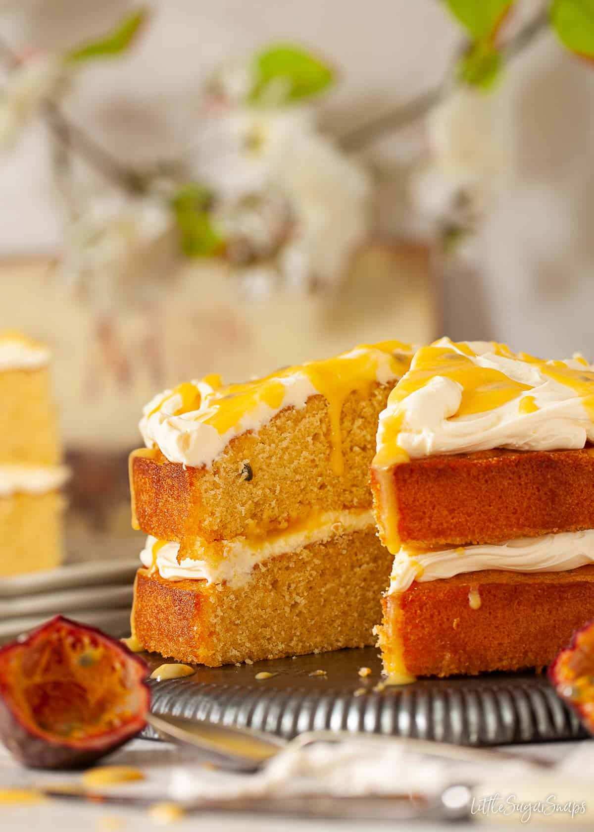 A passion fruit curd cake with a piece cut out of it.