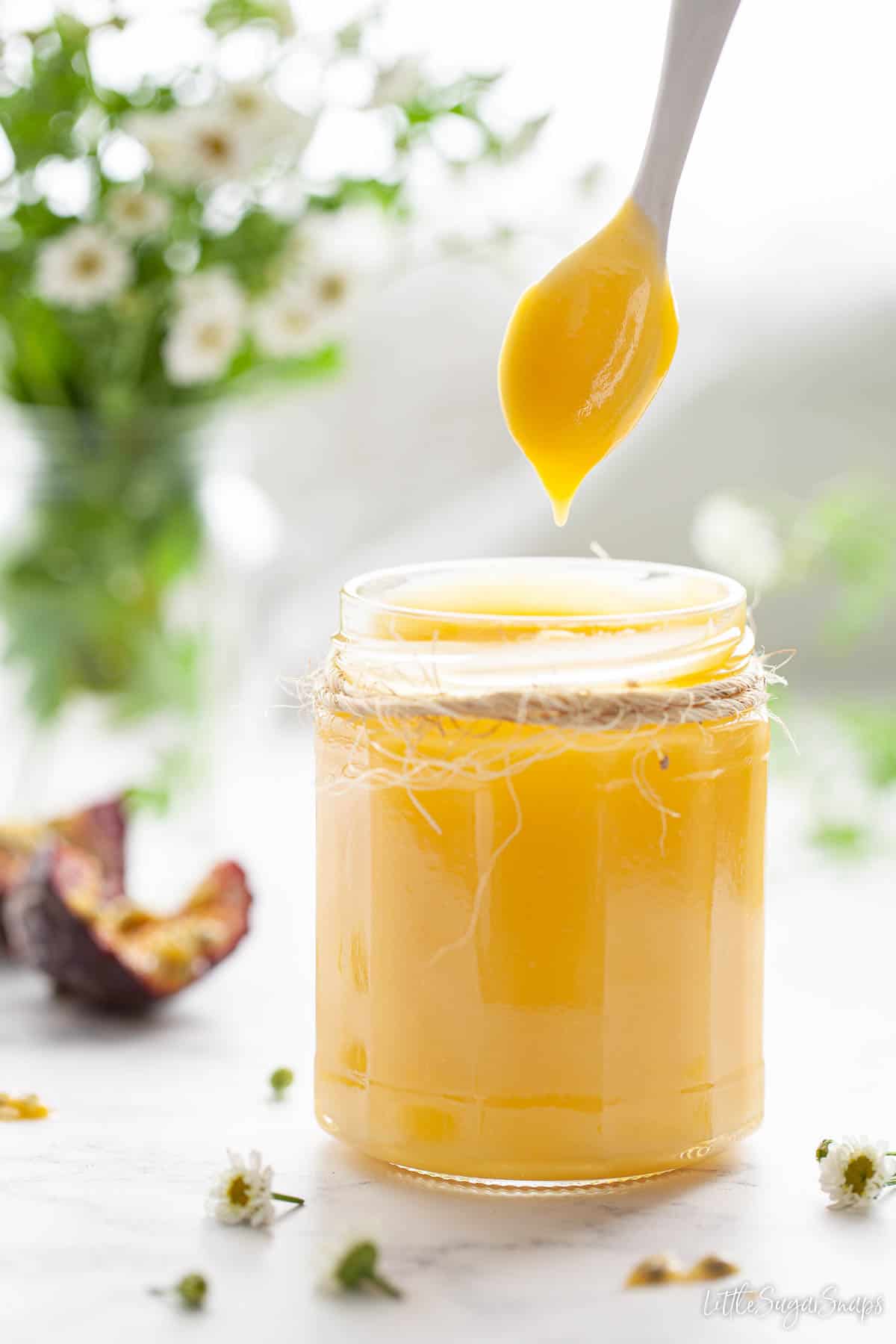 Passion fruit curd dripping from the end of a spoon