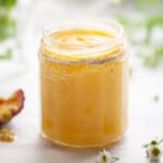 A jar of passion fruit curd in a jar with the lid off.