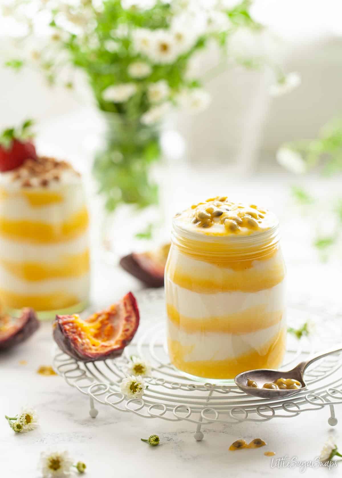 Jars filled with layers of yoghurt and passion fruit curd and topped with seeds.