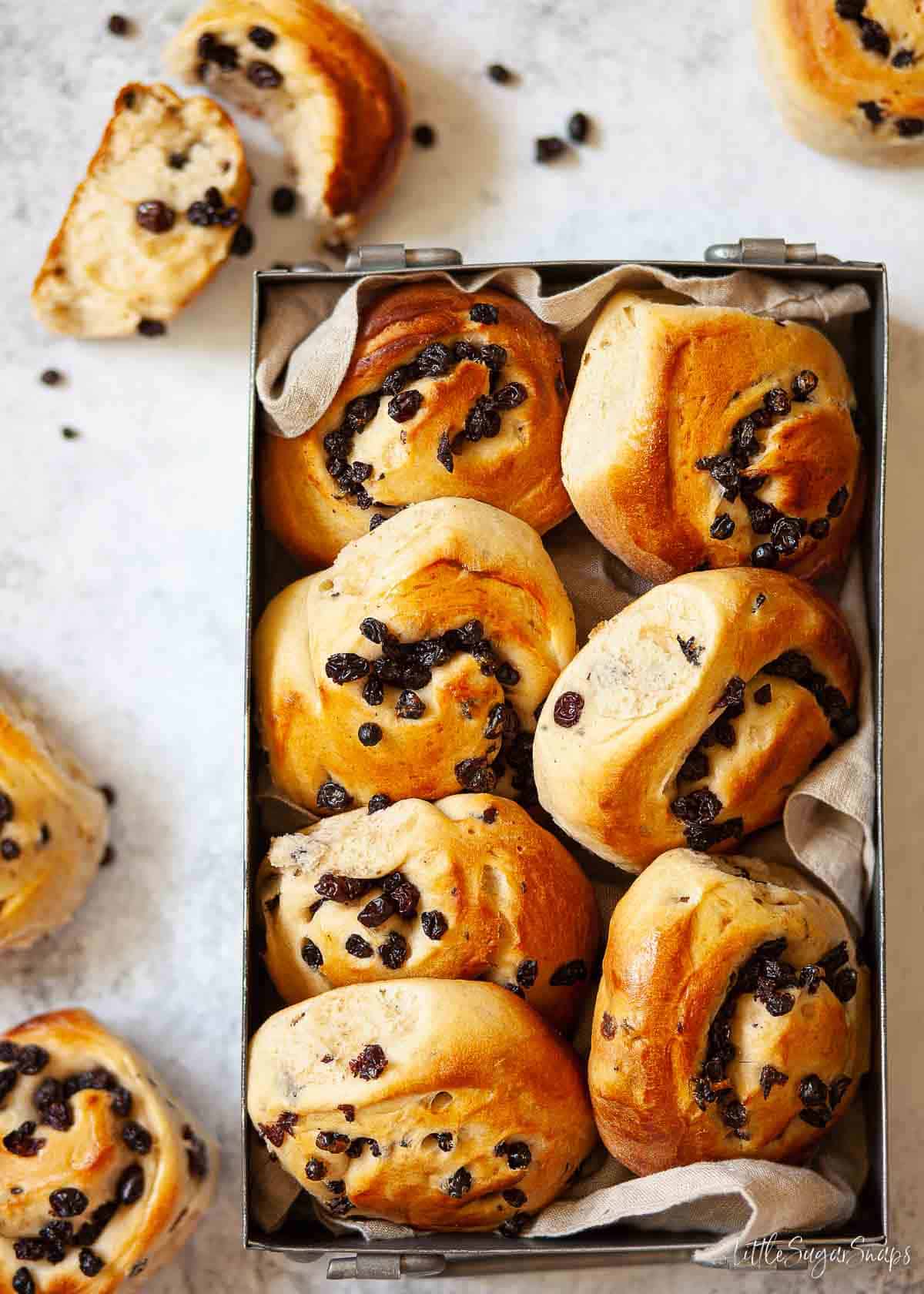 A tray of Belvoir Castle currant buns with one split open at the side.