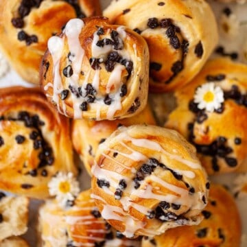 Close up of unglazed and glazed currant buns.