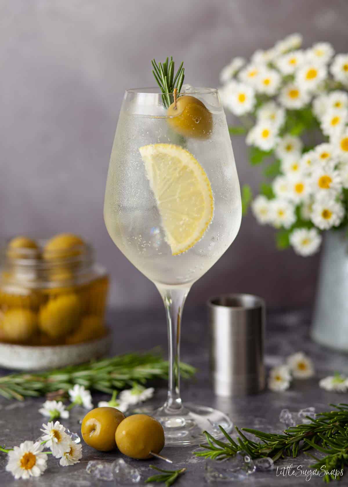 A spritz bianco with lemon, olive and rosemary garnish.