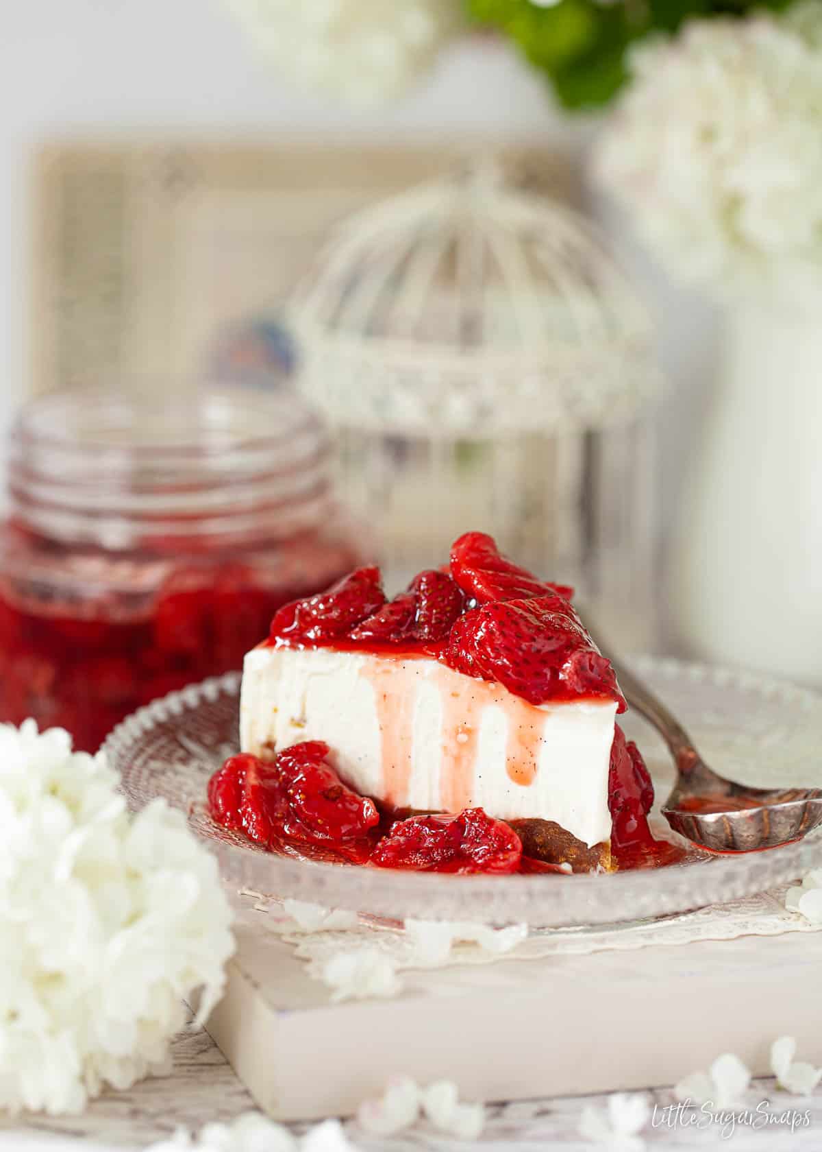 A slice of vanilla cheesecake topped with strawberry cheesecake sauce.