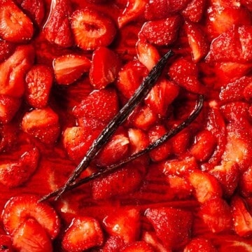 Roasted strawberry compote on a baking sheet with a vanilla pod.