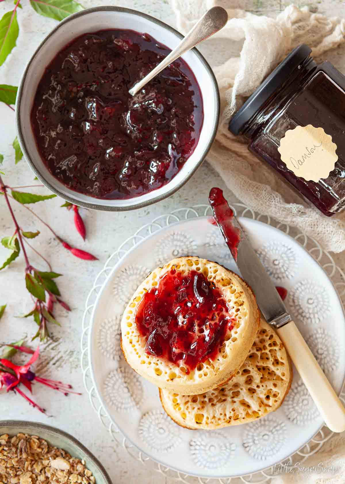 Damson jam spread on crumpets with a bowl of jam alongside.
