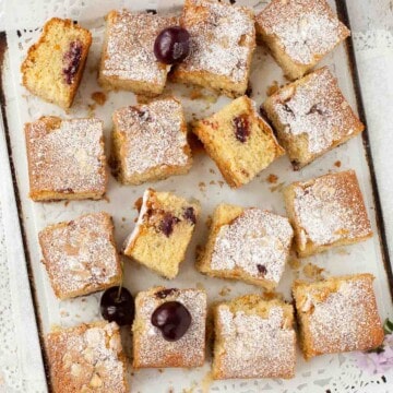 Squares of gluten-free cherry sponge cake on a baking sheet.