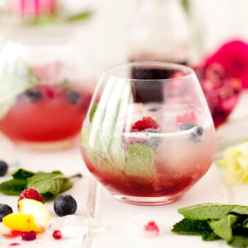 A sparkling pomegranate drink garnished with mint and raspberries.