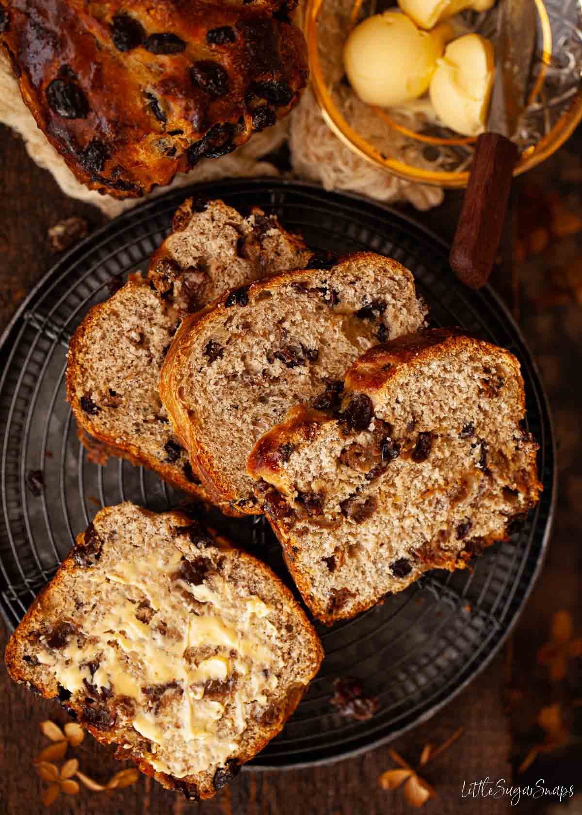 Slices of Lincolnshire plum bread on a plate. One slice has been buttered.