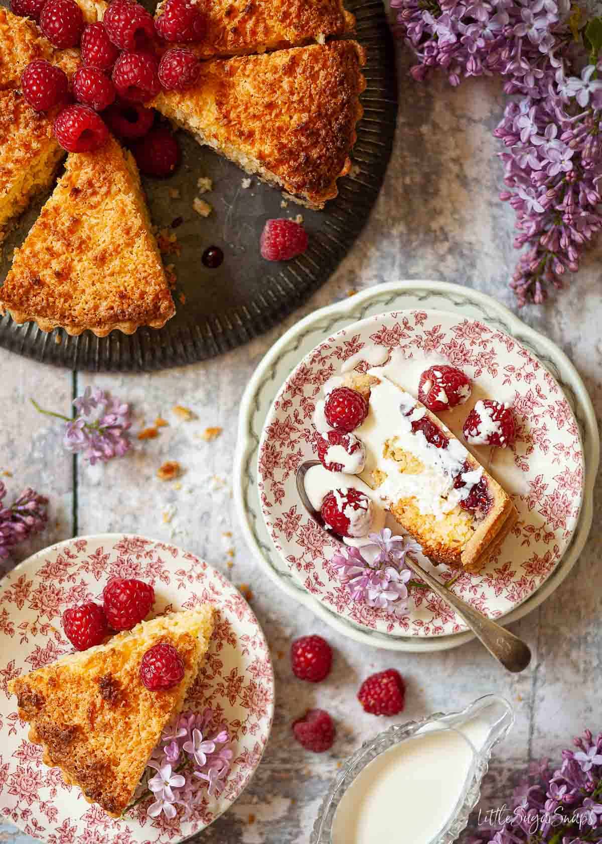 Slices of coconut tart with jam, served with single runny cream.