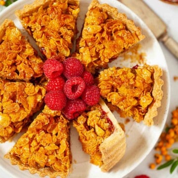 Close-up of school cornflake tart sliced and served with frsh raspberries.