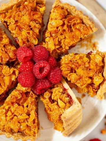 Close-up of school cornflake tart sliced and served with frsh raspberries.
