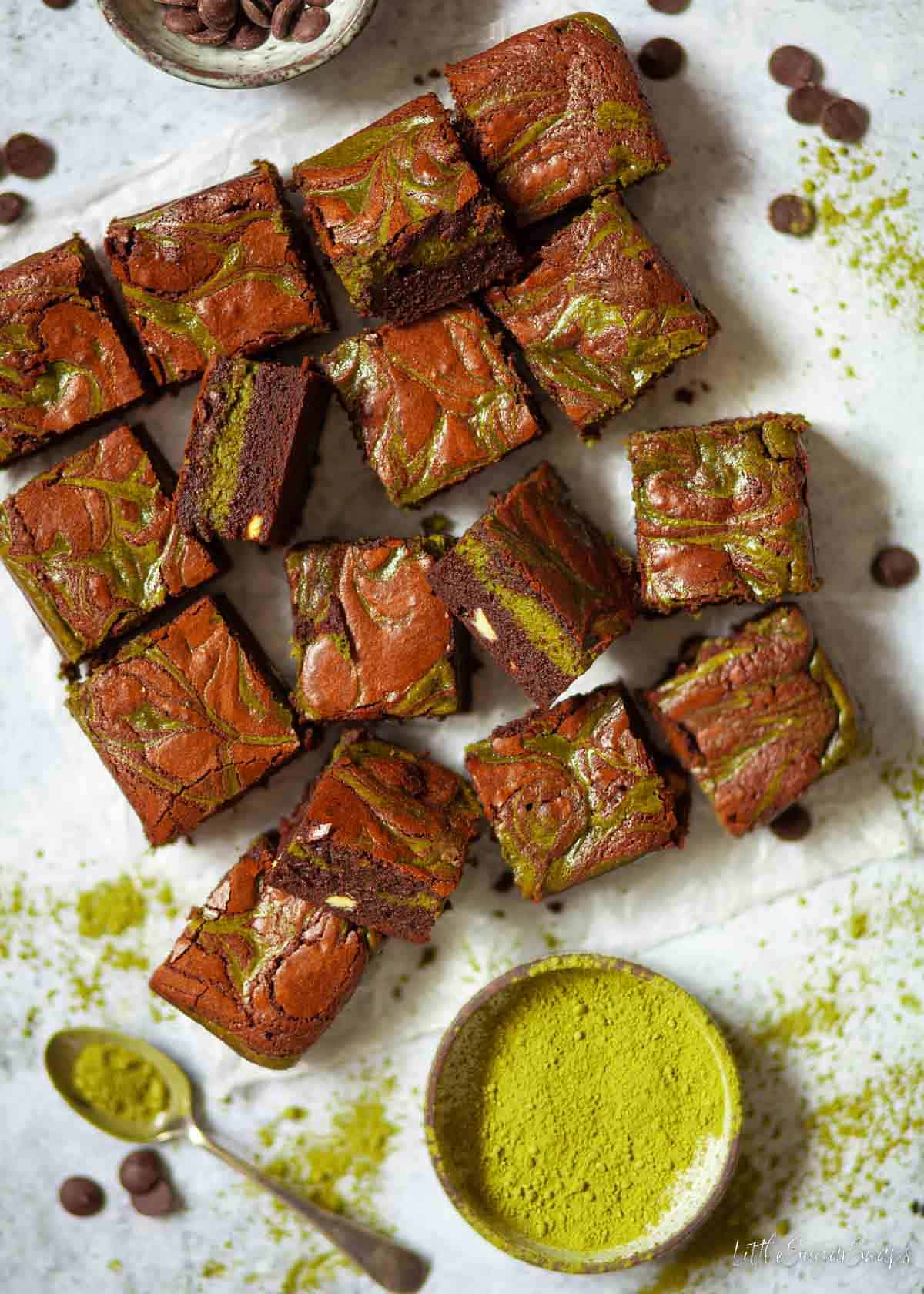 Matcha brownies cut into squares with a tin of matcha powder alongside.