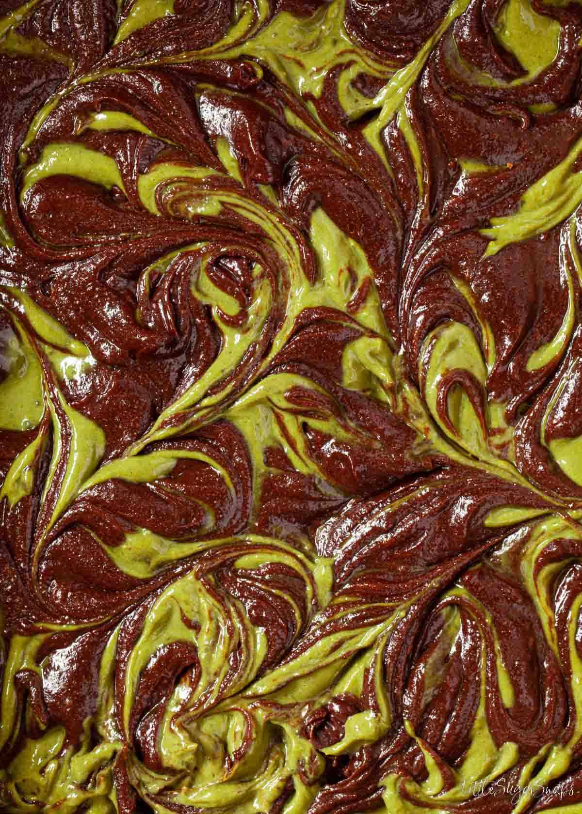 Close up of batter for a matcha brownie with the matcha cheesecake batter swirled in.