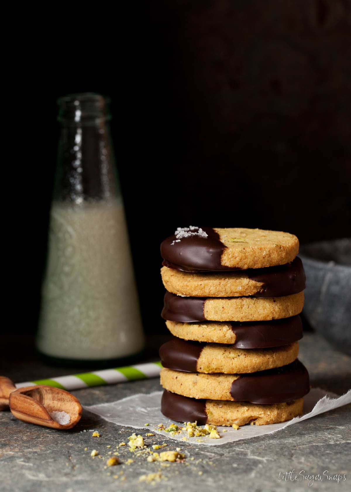 A stack of pistachio shortbread cookies with a bottle of milk.