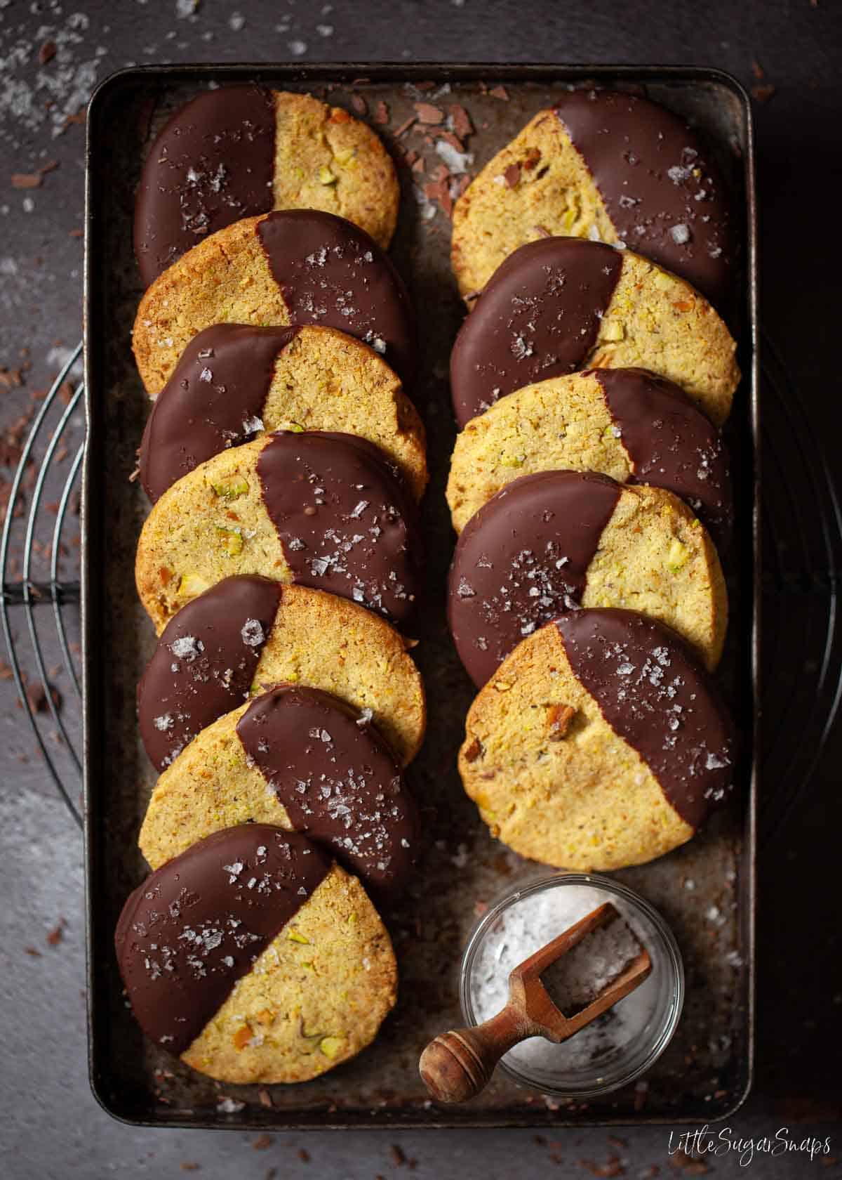 Pistachio biscuits half covered in dark chocolate and sprinkled with sea salt.