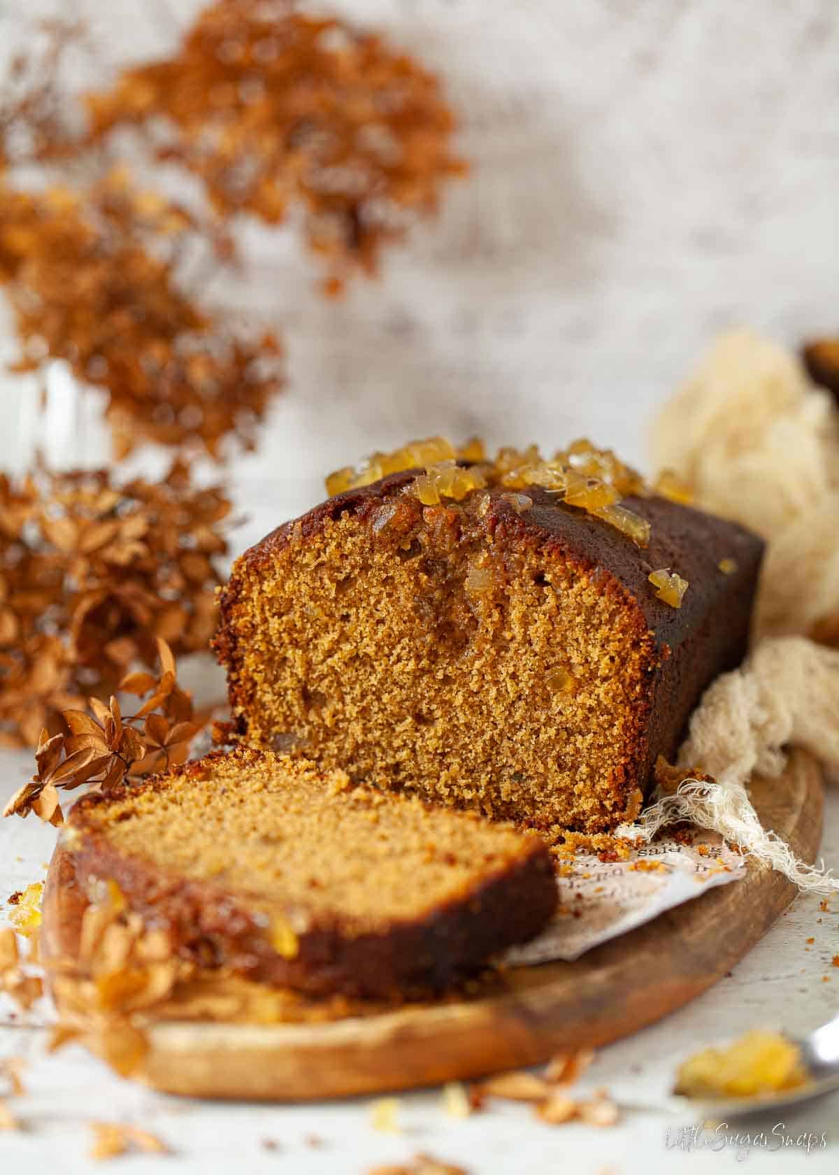 A ginger loaf cake cut into on a wooden board.