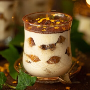 Close-up of a glass of tiramisu dessert topped with golden stars.