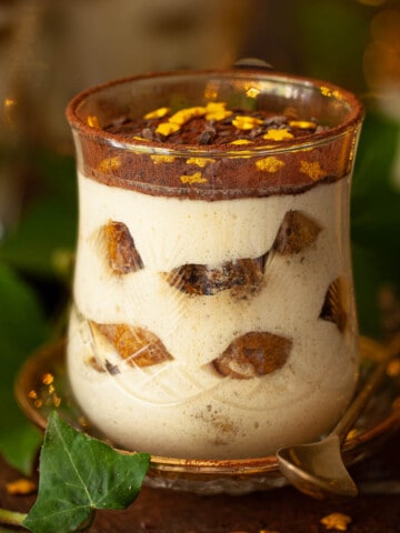 Close-up of a glass of tiramisu dessert topped with golden stars.