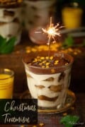 A glass of tiramisu with a lit sparkler and text overlay.