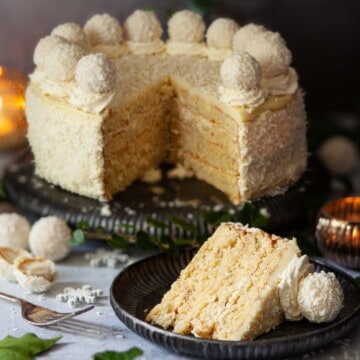 Close-up of a Raffaello cake (coconut almond torte) with a slice on a plate.