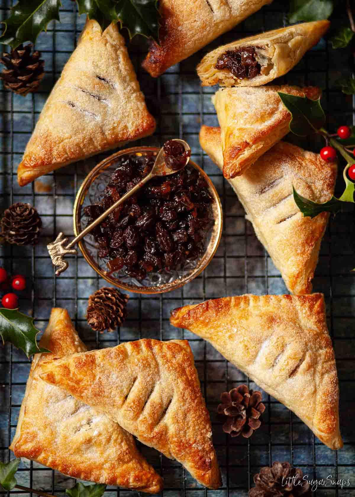 Mincemeat puff pastry turnovers on a wire rack with a saucer of mincemeat.