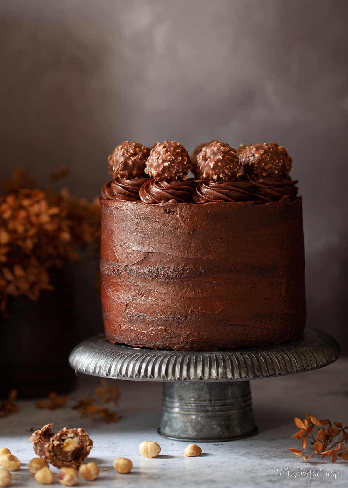 A Ferrero Rocher Cake covered in whipped chocolate ganache and decorated with chocolates.