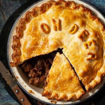 Close up of venison pie with a slice removed from the baking tin.