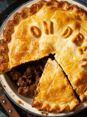 Close up of venison pie with a slice removed from the baking tin.