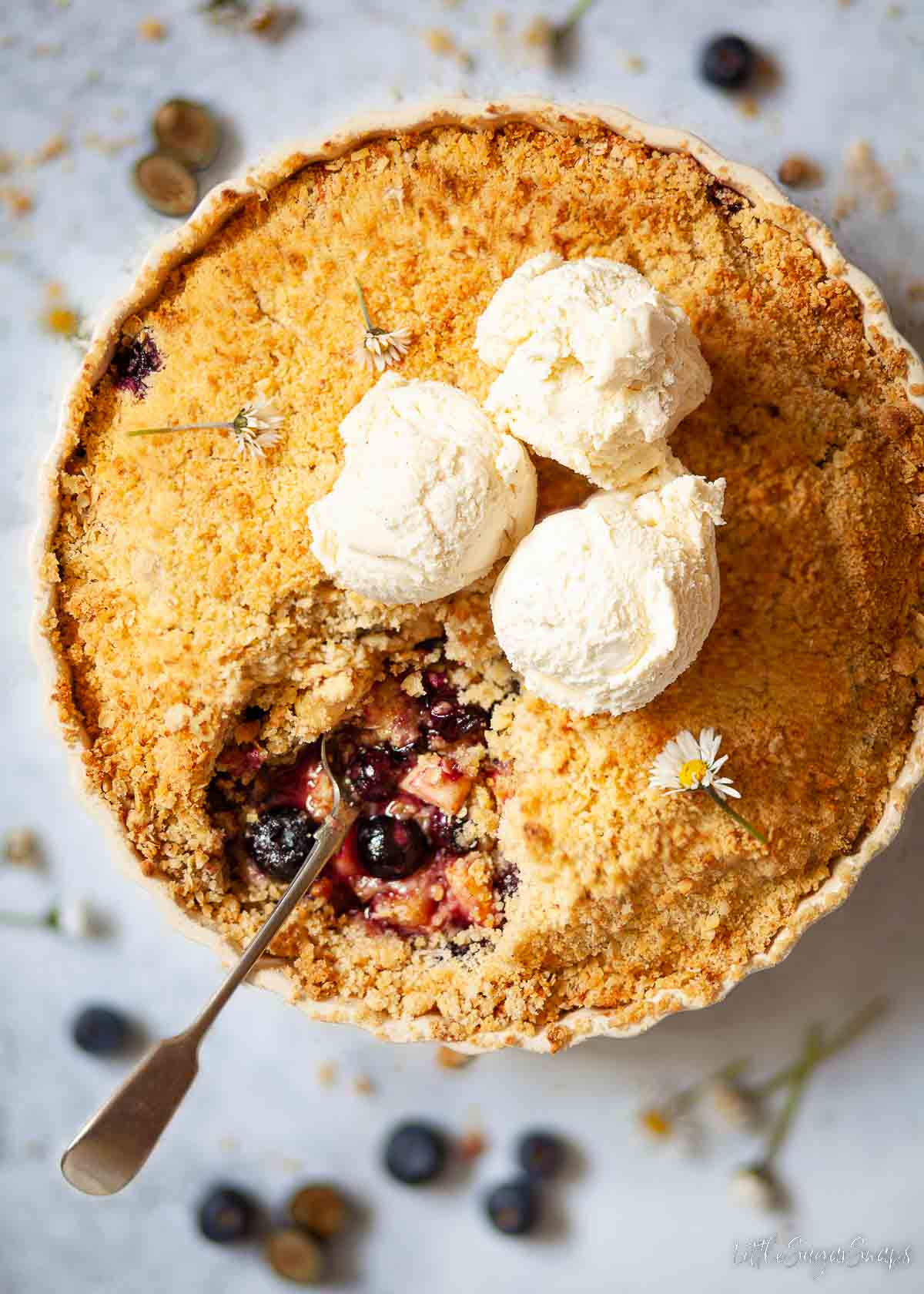 Blueberry and apple crumble and ice cream in a serving dish with a portion removed.