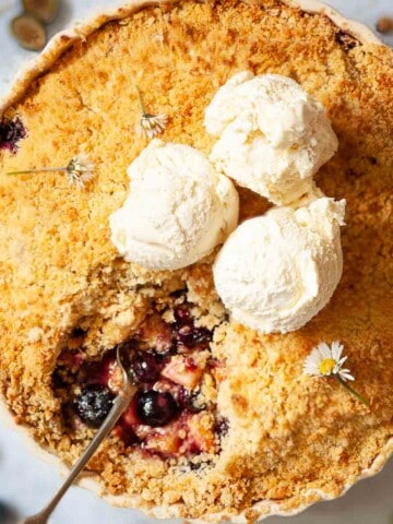 Close up of a large fruit dessert in a serving dish with a portion removed.