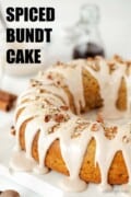 Labelled image of spiced bundt cake with cinnamon icing, nuts and toasted coconut on top.