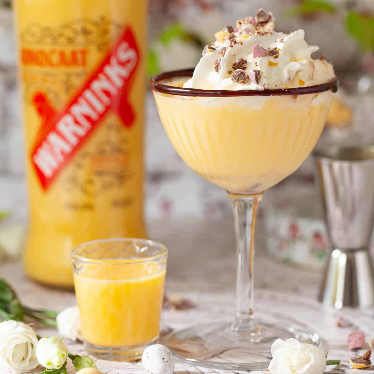 A yellow cocktail with advocaat decorated with whipped cream and easter eggs.