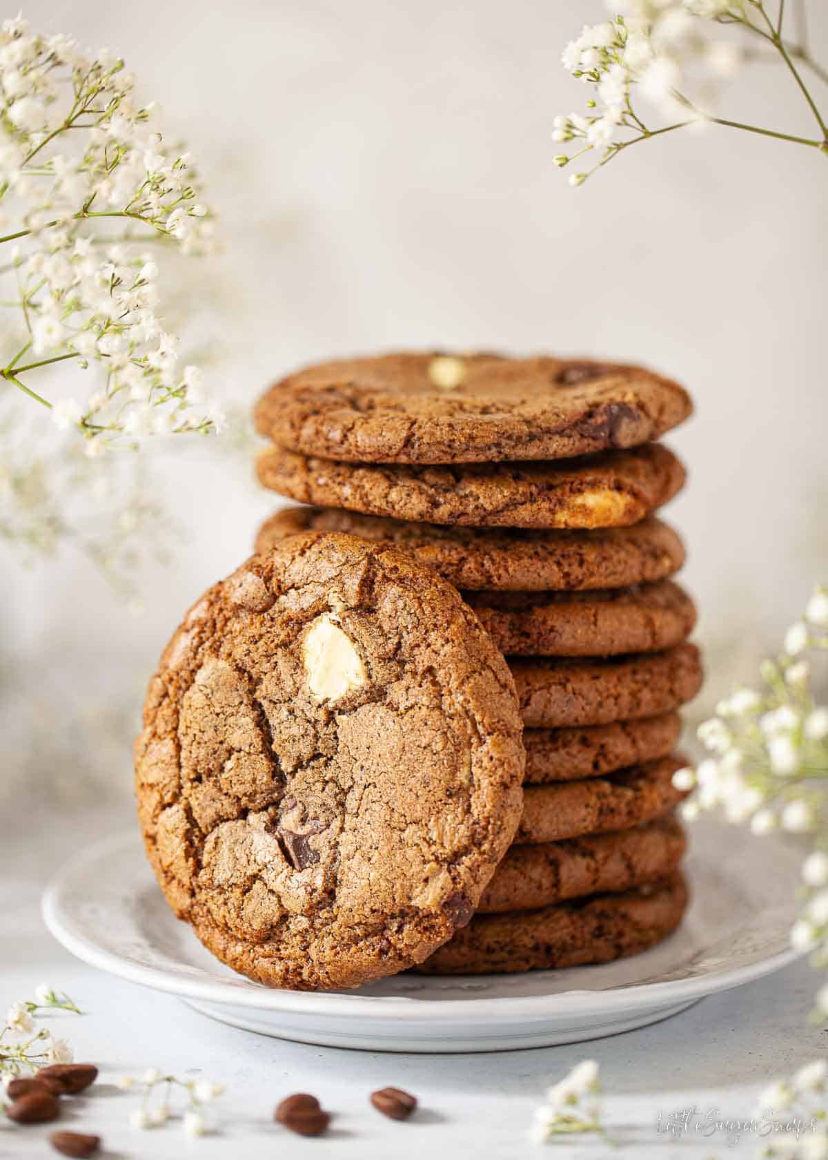 A stack of soft chocolate chip coffee cookies surrounded by white flowers.