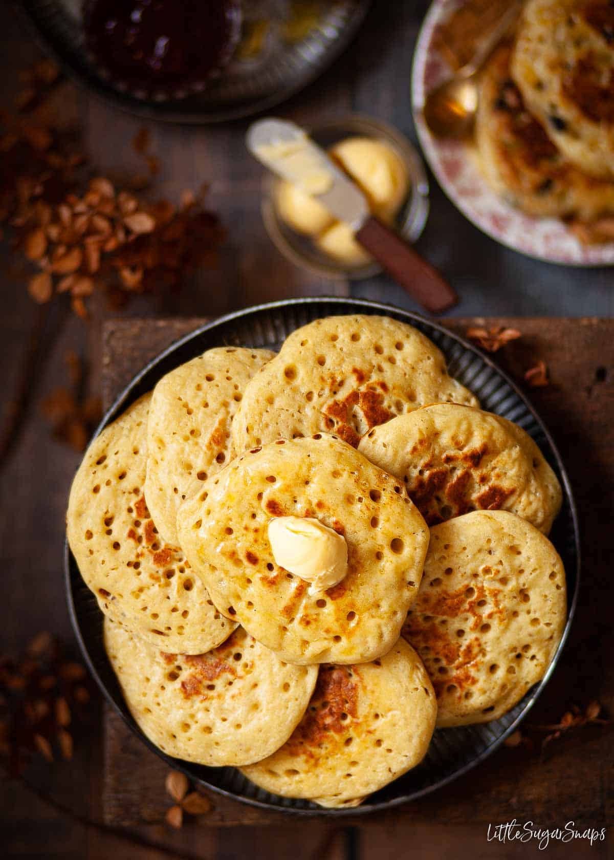 A plate of English pikelets, one of which has butter on the top.