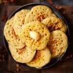 Close-up of pikelets on a plate with one on top with butter on it.