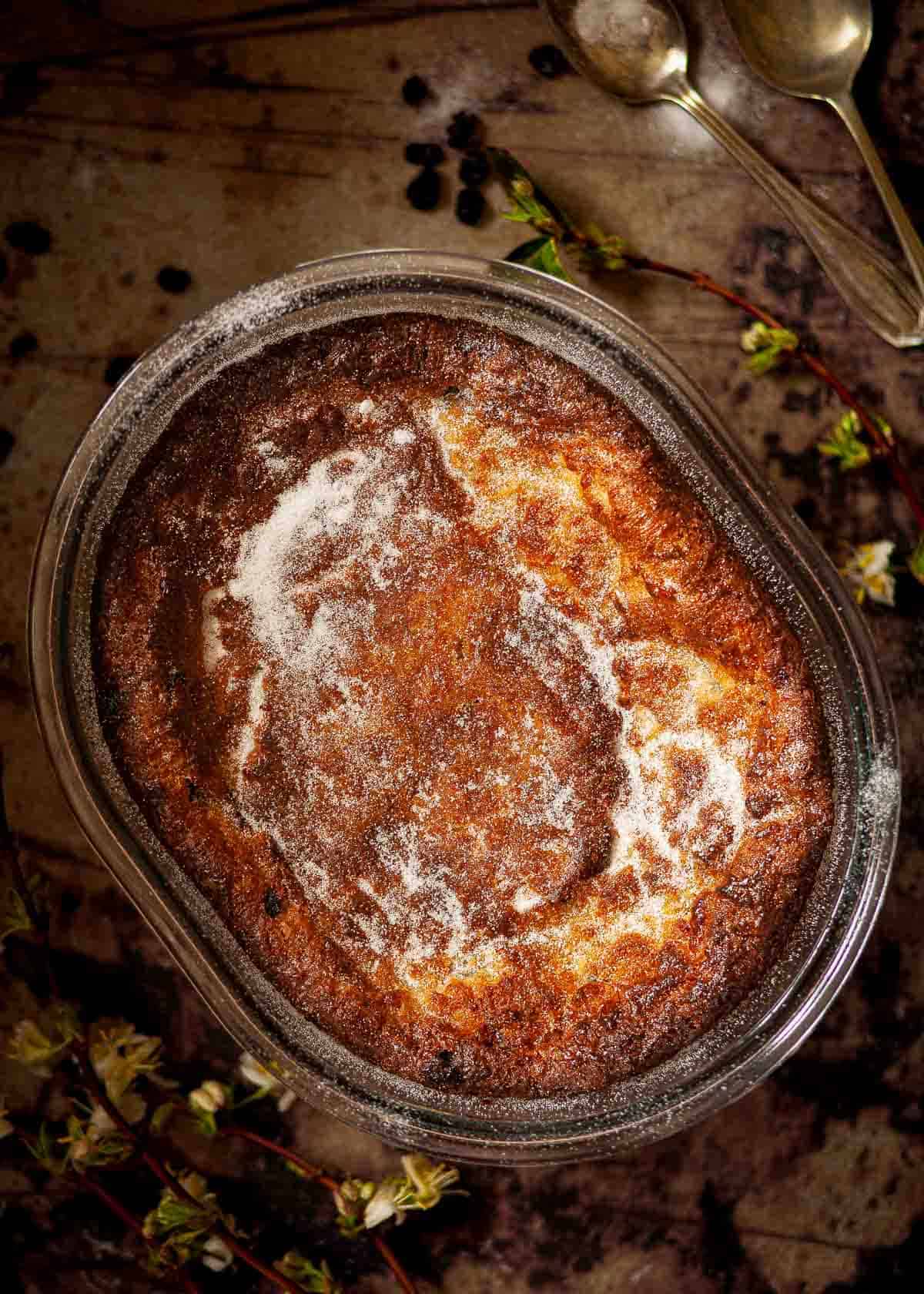 A baked suet pudding sprinkled with caster sugar in an oval serving dish.