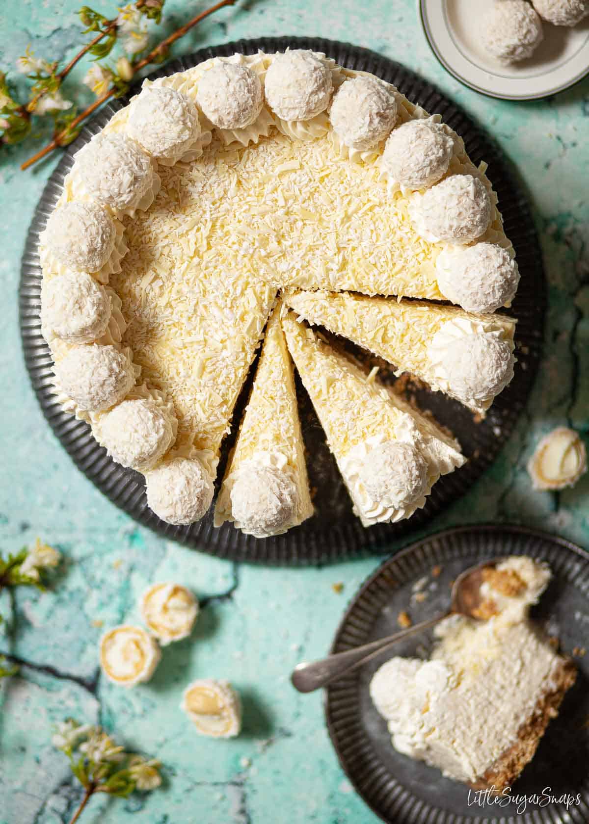 Raffaello cheesecake on a serving plate with three slices cut and ready to be served.