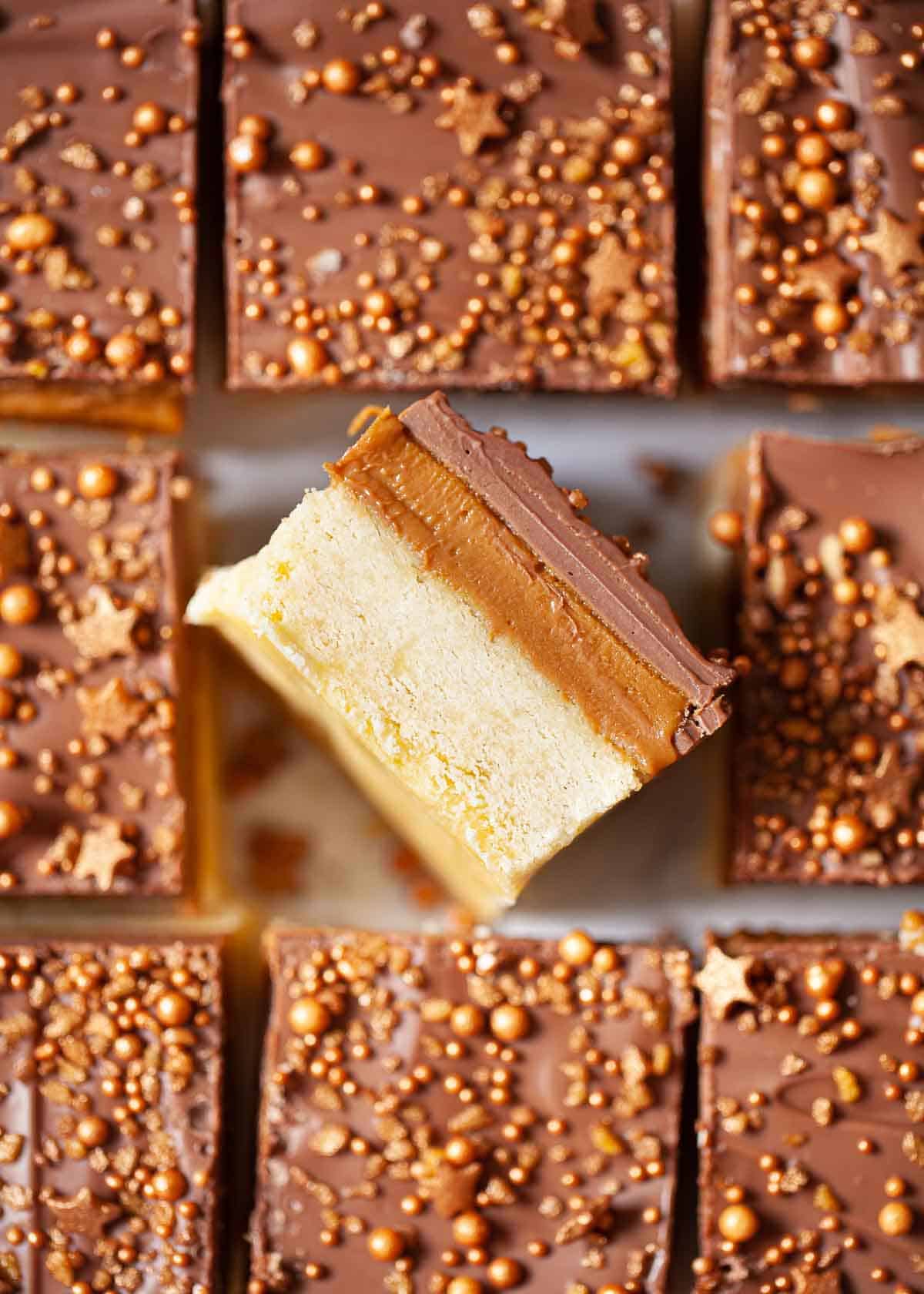 Squares of Biscoff millionaires shortbread topped with sprinkles. One square is on its side.