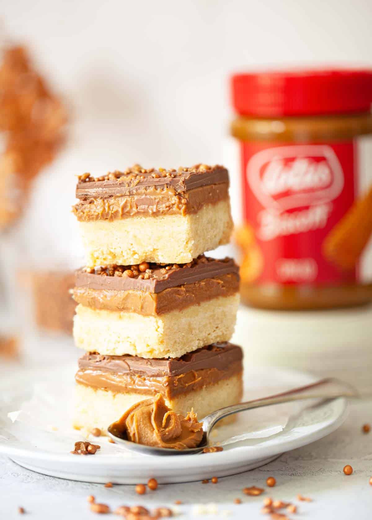 A stack of Biscoff slices with a jar of Biscoff spread in the background.