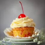 Close-up of a cherry cupcake with piped buttercream and a whole cherry on the top.