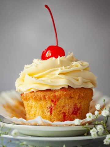 Close-up of a cherry cupcake with piped buttercream and a whole cherry on the top.