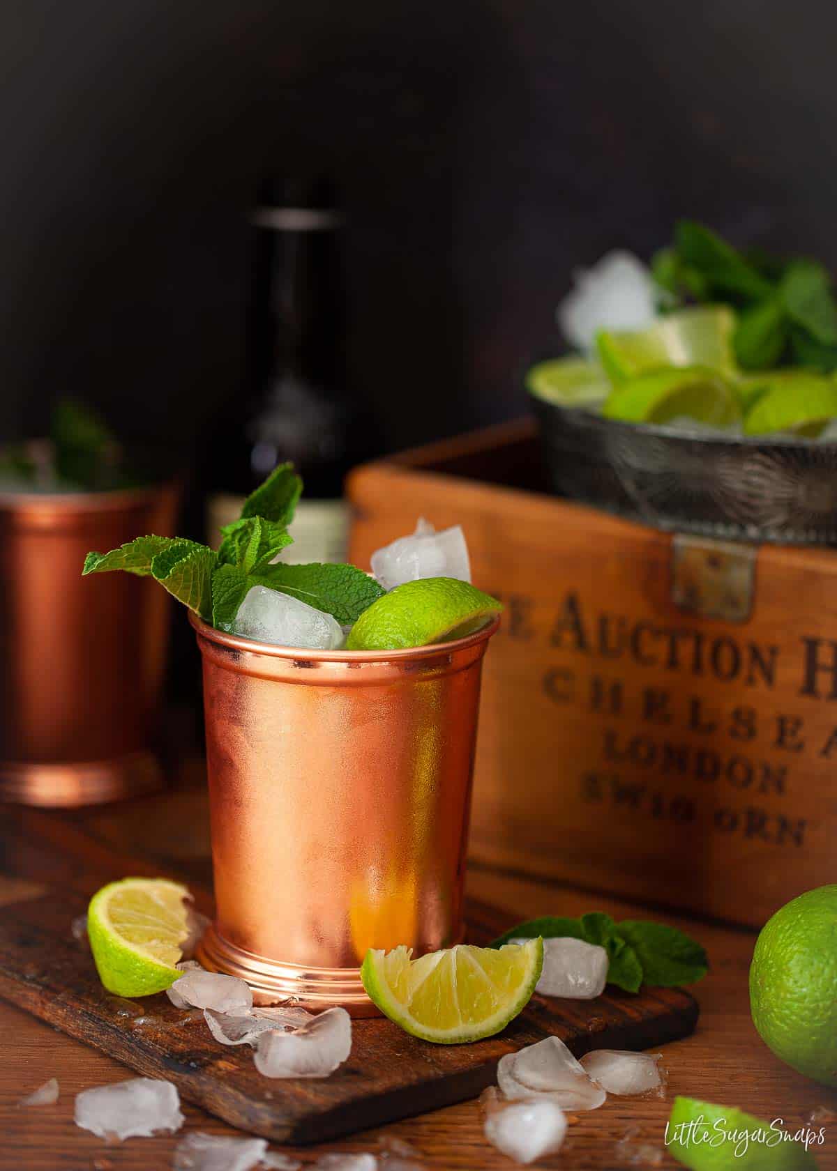 A London mule in a copper mug with lime and mint garnish and ice scattered around.