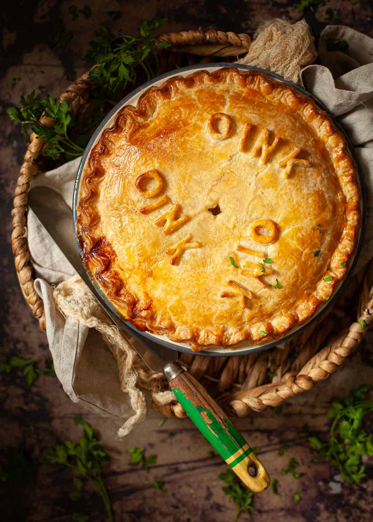 A whole sausagemeat pie ready to serve. It has been decorated with pastry letters spelling oink.