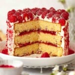 Close up of a white chocolate and raspberry cake with several slices cut from it.