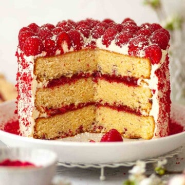 Close up of a raspberry and white chocolate cake with several slices cut from it.