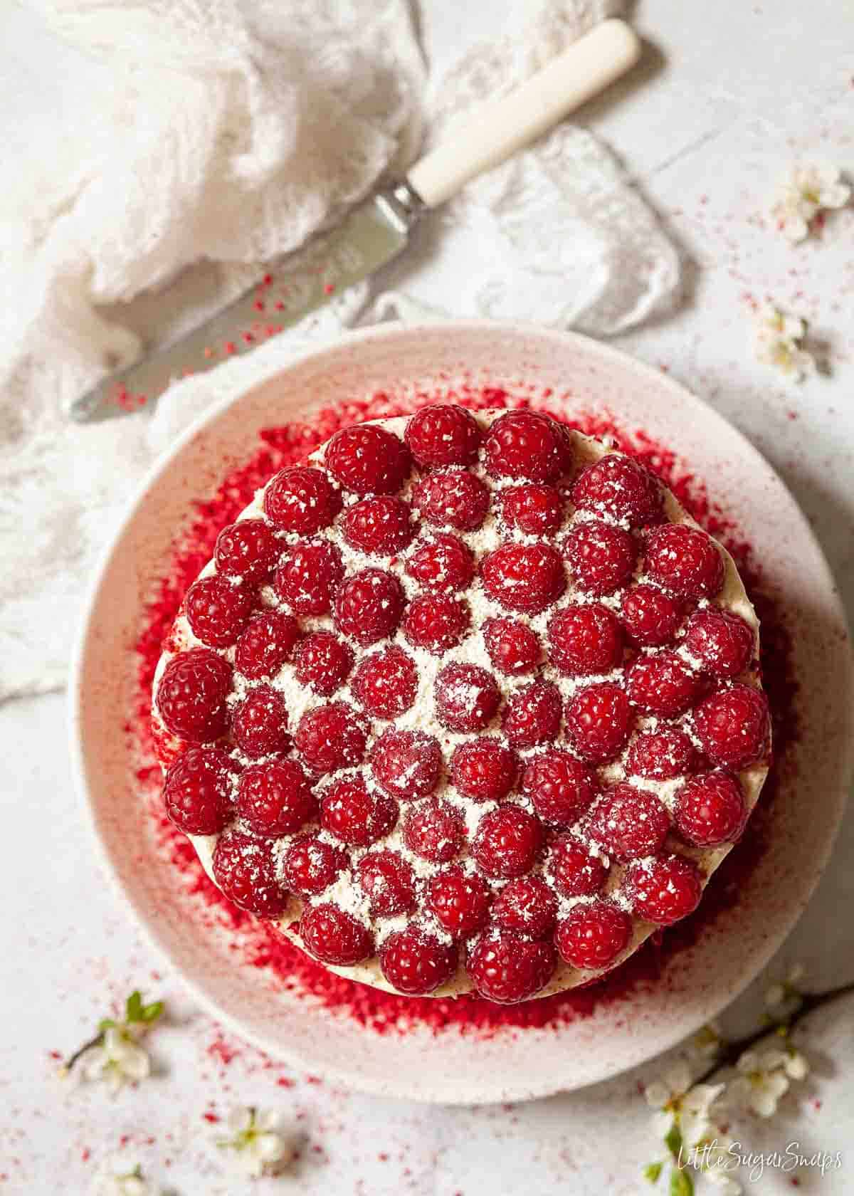 A large cake decorated with fresh berries and grated white chocolate.