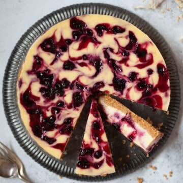Close up of a blackcurrant cheesecake with several slices cut from it.